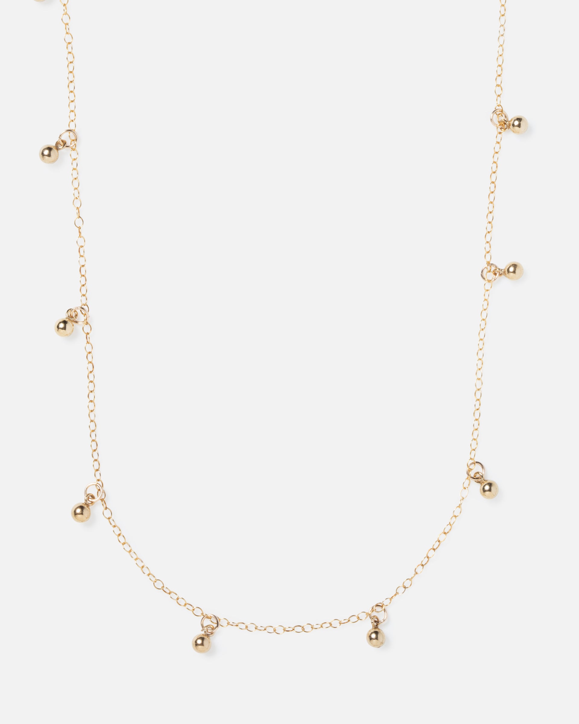 small gold ball charms hanging off of gold necklace